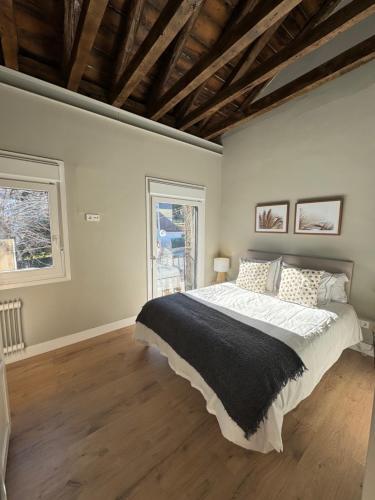 a bedroom with a large bed and two windows at La Casita de Lauri in Escorial