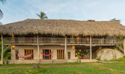 a house with a thatched roof and a large rock at Arrecifes Refugio Natural in Santa Marta