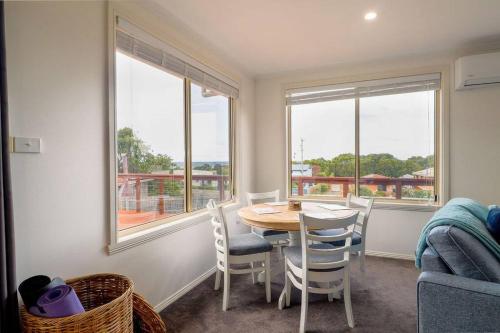 a dining room with a table and chairs and windows at Tides & Tails - Pet Friendly in Scamander