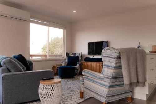 a living room with two chairs and a television at Tides & Tails - Pet Friendly in Scamander