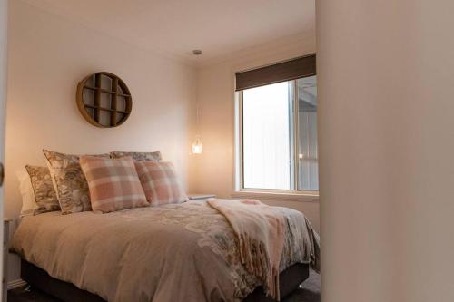 a bedroom with a bed with a mirror and a window at Tides & Tails - Pet Friendly in Scamander