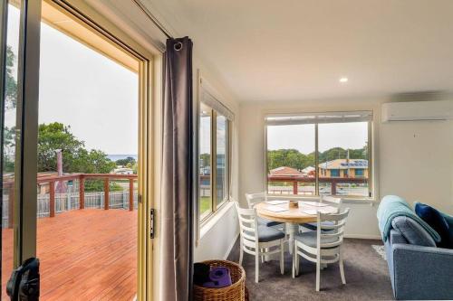 a room with a table and chairs and a balcony at Tides & Tails - Pet Friendly in Scamander