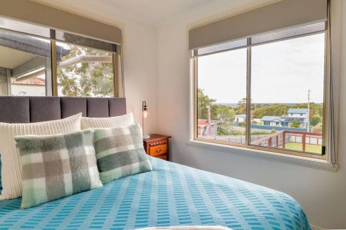 a bedroom with a bed with a view of the ocean at Tides & Tails - Pet Friendly in Scamander