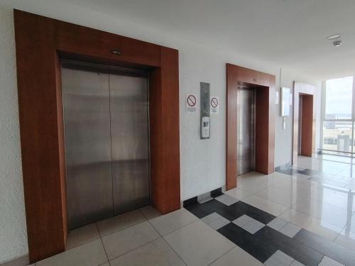 a hallway with two elevators in a building at J&K Guesthouse at Palmyra Residence in Kajang