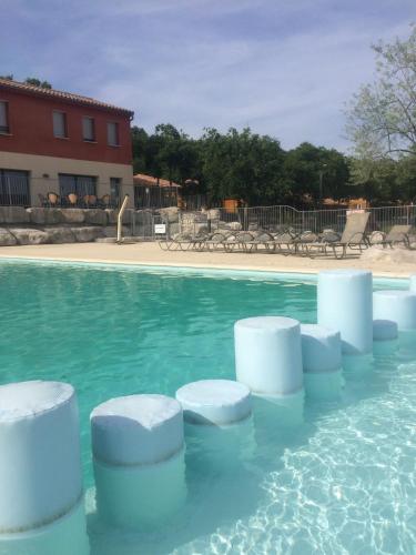 a swimming pool with white objects in the water at Rev'ôthijol Vacances in Saint Alban Auriolles