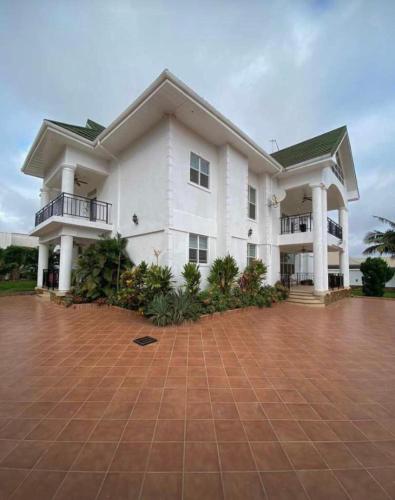 Una gran casa blanca con una entrada de ladrillo en Tranquil Haven Villa, en Kumasi
