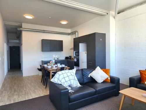 a living room with a leather couch and a table at U Suites on Webb in Wellington