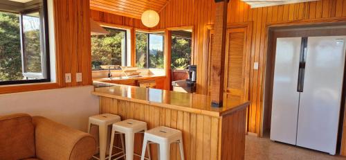 a kitchen with a counter with stools and a refrigerator at Tawa Whare holiday accommodation in Raglan