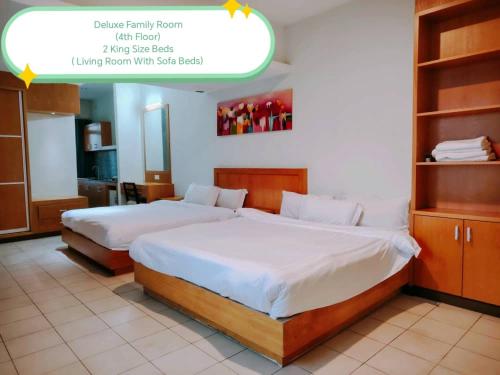 two beds in a hotel room with a sign above them at Fratini's Hotel Labuan in Labuan