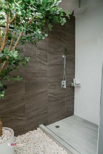 a shower with a glass door next to a tree at Blooming resort buriram บลูมมิ่ง รีสอร์ท บุรีรัมย์ in Ban Makha