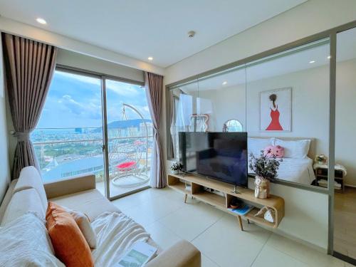 a living room with a tv and a large window at PƠ Homestay THESONG Vũng Tàu in Vung Tau