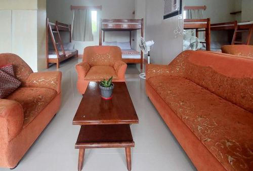 a living room with orange couches and a coffee table at RedDoorz at JL Lodging House and Cafe Irosin in Irosin