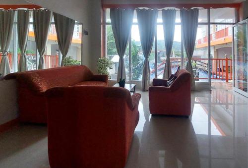 a living room with two couches and large windows at RedDoorz at JL Lodging House and Cafe Irosin in Irosin