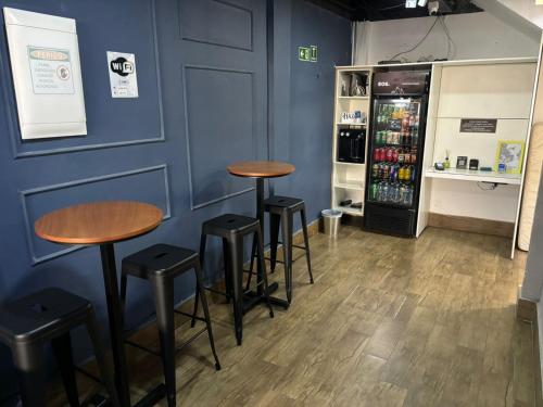 a blue wall with three bar stools and a refrigerator at Ház Portuguesa in Rio de Janeiro