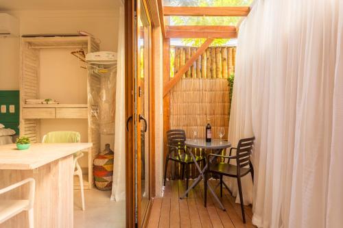 朱奎Casa d'Aroeira Residencial Boutique - Centro de Juqueí - 2 quadras do mar - Serviço de Praia - Roupa de Cama 600 fios algodão Egípcio - Toalhas Banho e Praia - Tudo Novo - Estacionamento Interno - Cozinha - Consulte unidades com Ofurô Hidro e Cromoterapia的一间有桌子、椅子和窗户的房间