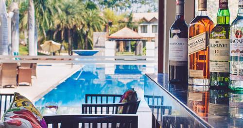 a group of bottles of wine sitting on a bar next to a pool at The Golkonda Resort and Spa in Hyderabad