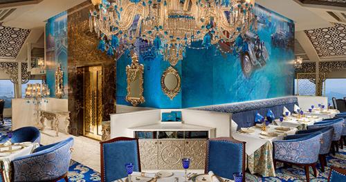 a dining room with blue walls and chandeliers at The Golkonda Resort and Spa in Hyderabad