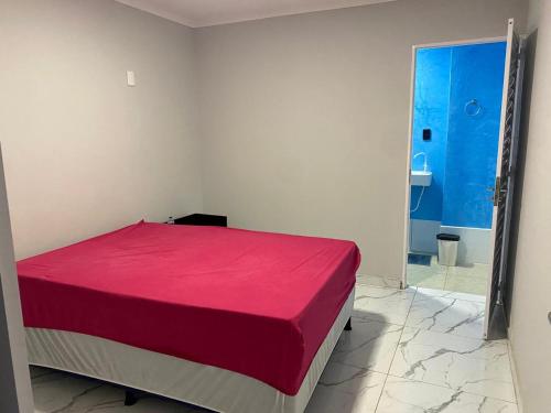 a bedroom with a red bed and a bathroom at Praia das Dunas SE in Estância