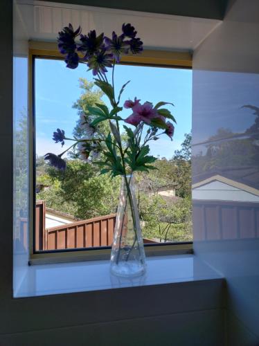 a vase with purple flowers sitting on a window sill at Tree Tops Studio Bangor in Bangor