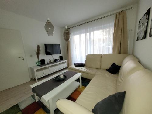 a living room with a white couch and a tv at Ballenstedt Gartenblick in Ballenstedt