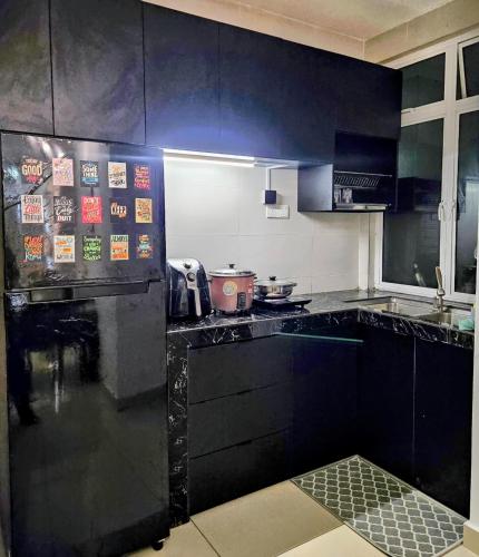 a kitchen with black cabinets with signs on it at The Avani Seroja Hills in Sepang
