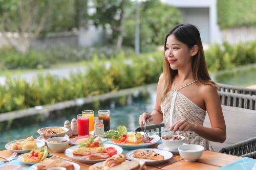een vrouw aan een tafel met eten bij Renaissance Pattaya Resort & Spa in Na Jomtien