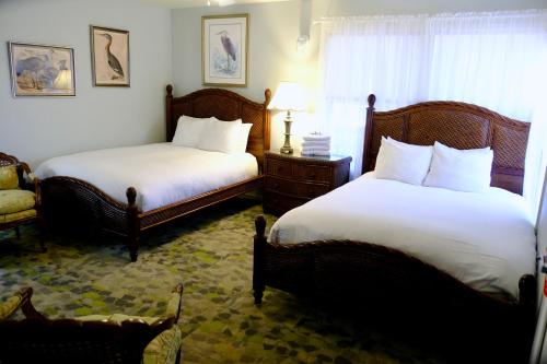 a bedroom with two beds and a chair and a window at Yosemite Bug Rustic Mountain Resort in Midpines