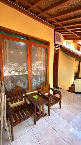 a porch with two benches and a table and a table and chairs at Rinjani Homestay in Pangandaran