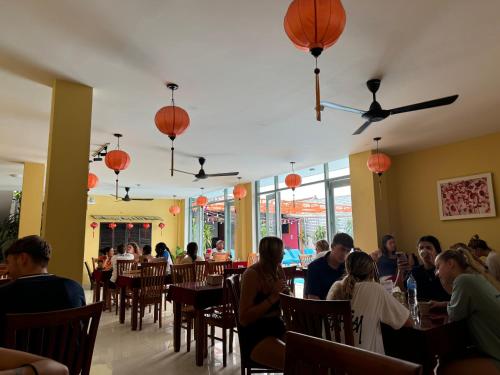 a group of people sitting at tables in a restaurant at Bed Station Hostel & Pool Bar Hội An " Former Sunflower" in Hoi An