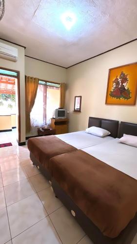 a hotel room with two beds and a television at Rinjani Homestay in Pangandaran
