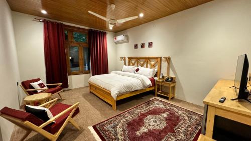 a bedroom with a bed and a desk and a television at The Pecan Resort in Gilgit