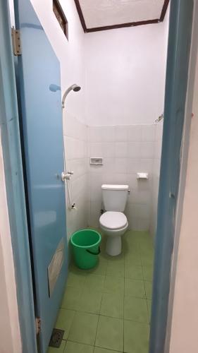 a bathroom with a toilet and a green bucket at Rinjani Homestay in Pangandaran