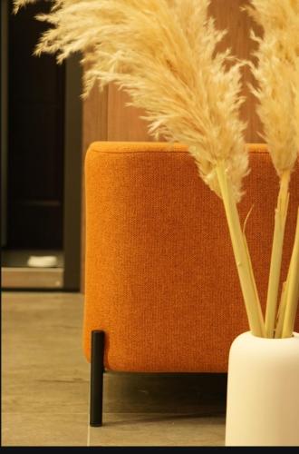 an orange chair sitting next to a vase with feathers at SkySpa Apartments - апартаменти з джакузі на терасі з видом на Печерськ in Kyiv