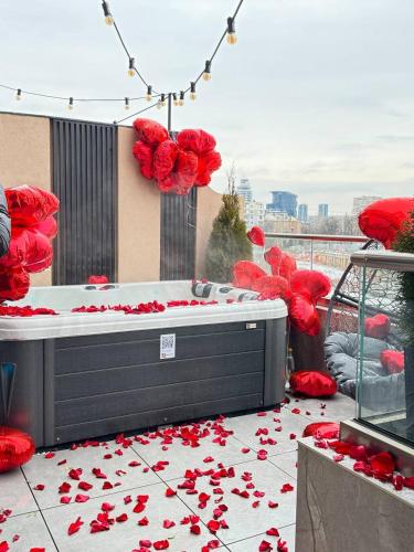 a bed with red rose petals on the ground at SkySpa Apartments - апартаменти з джакузі на терасі з видом на Печерськ in Kyiv
