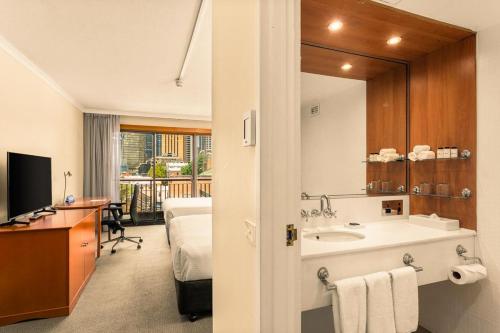 シドニーにあるSydney Harbour Hotelの洗面台、ベッド、鏡のあるバスルーム
