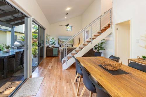 a dining room with a table and a staircase at Mobys 29 in Boomerang Beach