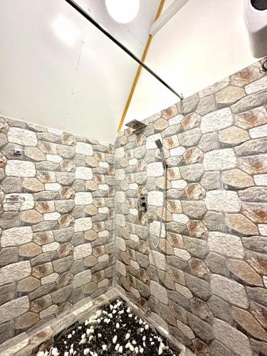 a bathroom with a stone wall with flowers at Rustic Cottages Udawalawe in Udawalawe