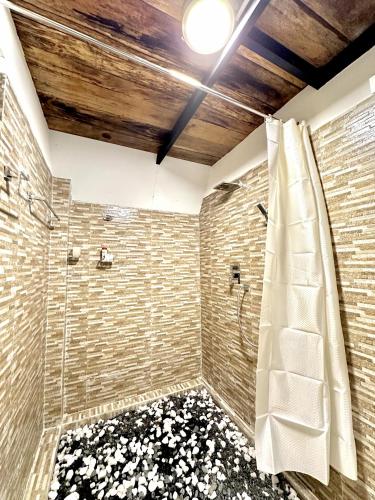 a bathroom with a shower with a stone wall at Rustic Cottages Udawalawe in Udawalawe