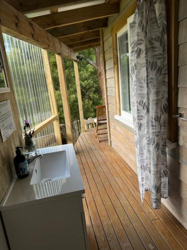 a porch of a cabin with a sink and a window at Private Cabin close to the City Centre in Whangarei