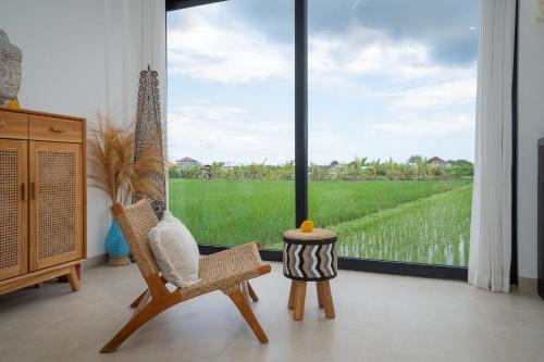 a room with two chairs and a large window at Villa Sawahku - 2 Bedrooms Private Villa with Rooftop and View in Canggu