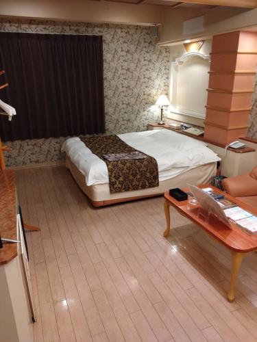 a bedroom with a large bed and a table at HotelおとぼけビーバーPREMIUM in Himeji