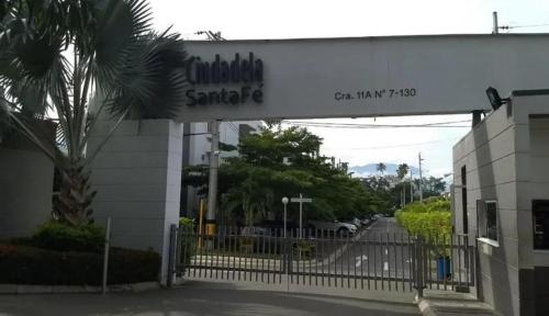 a sign for a building with a gate and a palm tree at Hermoso apartasol en santafe de Antioquia. in Santa Fe de Antioquia