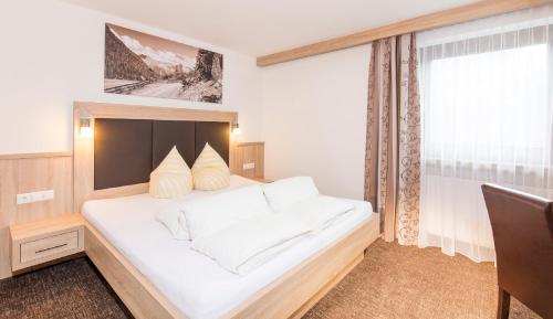 a bedroom with a large white bed with a window at Gästehaus Emil in Sölden
