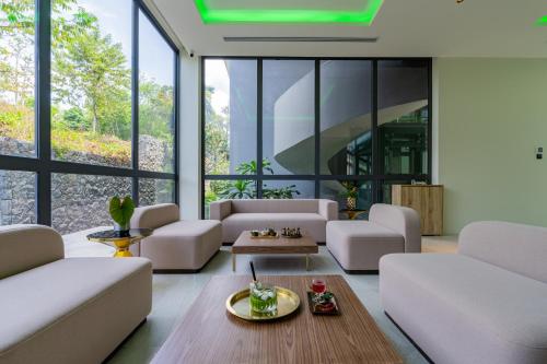 a living room with white furniture and large windows at La Green Hotel and Residence in Bang Tao Beach