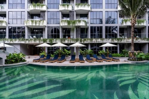a hotel swimming pool with chairs and umbrellas at La Green Hotel and Residence in Bang Tao Beach