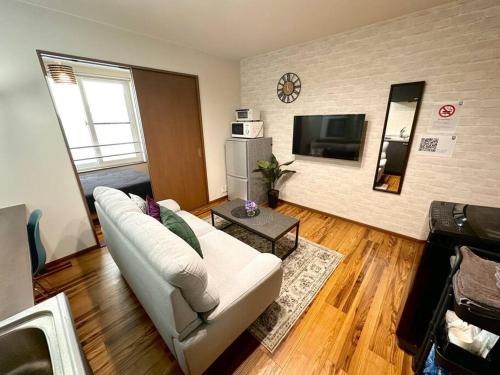 a living room with a white couch and a television at SapporoCity Ark Coat 203 in Minami-jūichijō