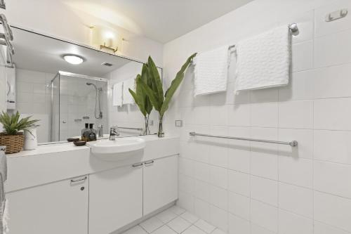 Un baño blanco con lavabo y espejo. en Picture Point 2 - 500m to Hastings St & Noosa Beach, en Noosa Heads