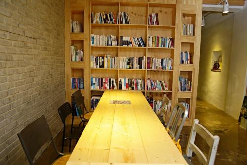 a long wooden table in a room with bookshelves at OP 102 Guesthouse in Gyeongju