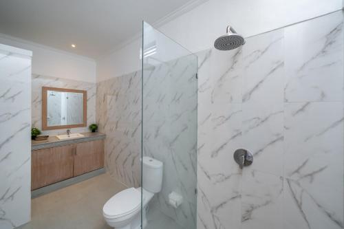 a bathroom with a toilet and a glass shower at Villa Margherita 3 Bedroom Canggu Swimming Pool in Canggu