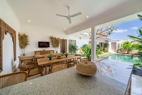 an open living room with a dining table and a swimming pool at Villa Margherita 3 Bedroom Canggu Swimming Pool in Canggu